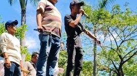 Seorang orator muda berteriak lantang dari atas mobil komando, suaranya memecah suasana. Massa berdesakan di bawah, wajah-wajah mereka penuh kemarahan. “Rp21 miliar bukan angka kecil, itu hak kami!” teriaknya, disambut sorakan membahana