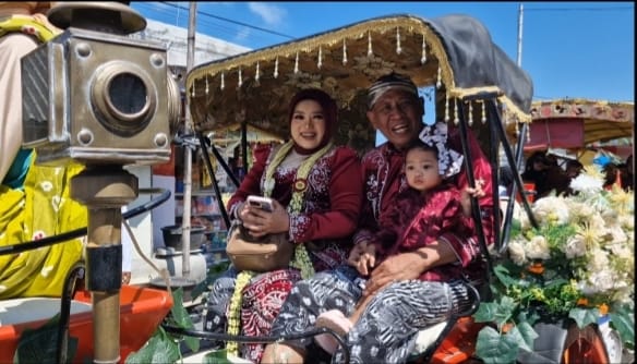 Suasana kemeriahan Karnaval HUT RI ke-80 di Desa Pinggir Papas. Ribuan warga antusias menyaksikan penampilan Kades dan istri yang tampil layaknya raja dan ratu