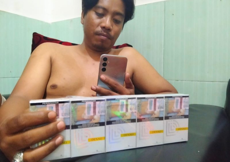 Syaiful Bahri menunjukkan bukti pembelian rokok One Point di stand PR Bahagia, Kamis malam (28/08/2025). Produk lokal Madura ini kian mencuri perhatian berkat harga terjangkau dan kemasan mewah.