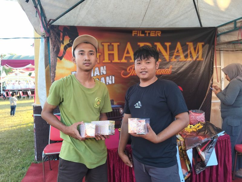 Dua pekerja PR Mulia Indah, memperlihatkan bukti produk HM Cokelat dan Rokok SKT-SKM Gharnam di stand Festival Tembakau Madura 2025. Aksi ini menegaskan kualitas dan keaslian produk lokal yang siap bersaing di pasar nasional