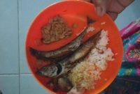 Dua siswa SDN Pabian IV tampak membawa pulang lauk ikan pindang dan tempe usai jam makan siang, Kamis (30/12/2025). Menu Program Makan Bergizi (MBG) hari itu dikeluhkan karena dinilai kurang layak dan tidak diminati anak-anak.
