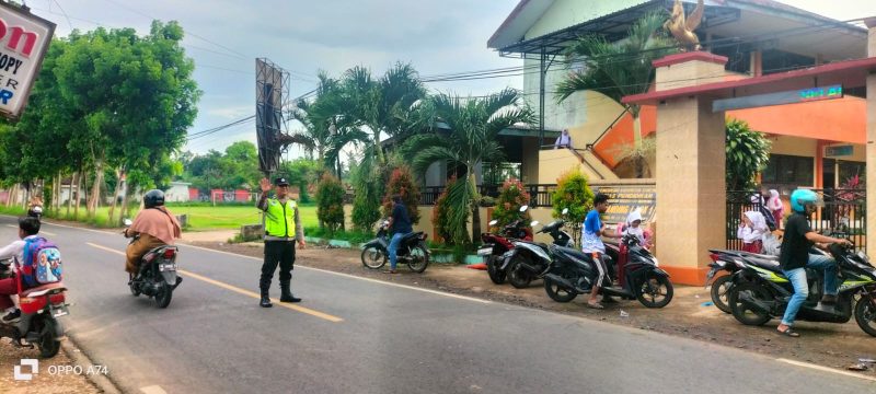 Aipda Agus Junaidi sigap membantu siswa SDN Manding Laok I menyeberang jalan dengan aman, setiap pagi, menunjukkan pengabdian nyata polisi untuk keselamatan anak-anak
