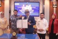 Kolaborasi Penguatan Ekonomi Daerah. Dekan Fikom Unitomo, Harliantara (tengah, bertopi), berjabat tangan dengan perwakilan Pemkab Halmahera Utara menandai dimulainya kerja sama dalam mendukung hilirisasi kelapa.
