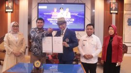 Kolaborasi Penguatan Ekonomi Daerah. Dekan Fikom Unitomo, Harliantara (tengah, bertopi), berjabat tangan dengan perwakilan Pemkab Halmahera Utara menandai dimulainya kerja sama dalam mendukung hilirisasi kelapa.
