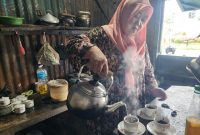 Ibu Sumiati, owner Kopi Peceng, tampak menuangkan air panas dalam proses penyeduhan kopi di warung pojok depan Hotel Myze Sumenep, mempertahankan cita rasa kopi tradisional yang konsisten sejak 2012.