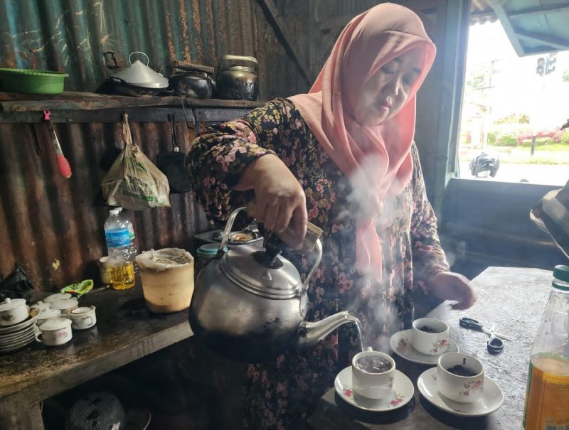 Ibu Sumiati, owner Kopi Peceng, tampak menuangkan air panas dalam proses penyeduhan kopi di warung pojok depan Hotel Myze Sumenep, mempertahankan cita rasa kopi tradisional yang konsisten sejak 2012.