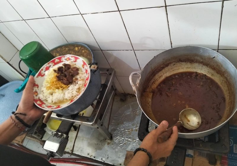 Ubai Bani menunjukkan aktivitas dapur Warung Nasi Pak Ending di Jalan Raya Gapura, Desa Bangkal, Sumenep. Warung legendaris penyaji nasi gule sapi ini telah bertahan sejak era penjajahan Belanda dan kini dikelola oleh generasi kedua.