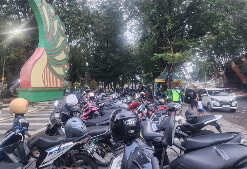 Puluhan sepeda motor tertata rapi di Taman Adipura Sumenep, diatur oleh tukang parkir yang tengah bertugas. Selama Festival Bazar Takjil Ramadan, mereka ikut merasakan berkah Ramadan dengan penghasilan Rp150–200 ribu per hari, sambil membantu menjaga ketertiban dan kebersihan area parkir.