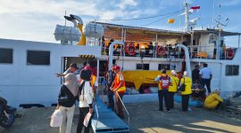 Petugas pelabuhan membantu penumpang menaiki kapal, memastikan perjalanan mudik gratis berjalan lancar dan aman.
