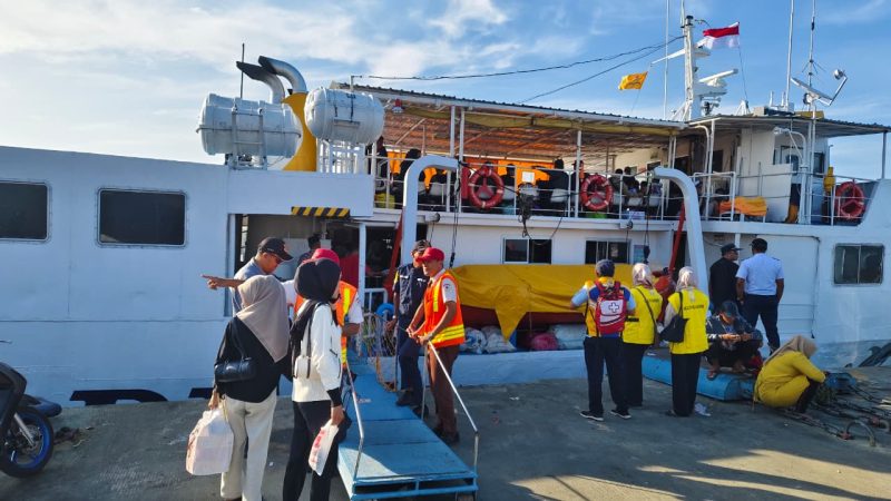 Petugas pelabuhan membantu penumpang menaiki kapal, memastikan perjalanan mudik gratis berjalan lancar dan aman.