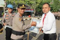 Kapolres Sampang AKBP Hartono menyerahkan penghargaan kepada Kasatreskrim Iptu Nur Fajri Alim atas keberhasilan mengungkap 27 kasus asusila terhadap anak dan sindikat curanmor di 31 TKP saat upacara di Mapolres Sampang, Rabu (15/7/2026).