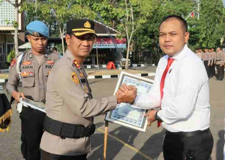 Kapolres Sampang AKBP Hartono menyerahkan penghargaan kepada Kasatreskrim Iptu Nur Fajri Alim atas keberhasilan mengungkap 27 kasus asusila terhadap anak dan sindikat curanmor di 31 TKP saat upacara di Mapolres Sampang, Rabu (15/7/2026).