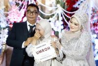 Ket Foto: Penerima hadiah paket umrah menangis haru saat nomor undiannya dibacakan langsung oleh H. Bambang Budianto. Momen penuh haru tersebut diapit kedua mempelai, H. Bambang Budianto dan Hj. Dian Mariana, dalam resepsi pernikahan di Banyuwangi.