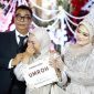 Ket Foto: Penerima hadiah paket umrah menangis haru saat nomor undiannya dibacakan langsung oleh H. Bambang Budianto. Momen penuh haru tersebut diapit kedua mempelai, H. Bambang Budianto dan Hj. Dian Mariana, dalam resepsi pernikahan di Banyuwangi.